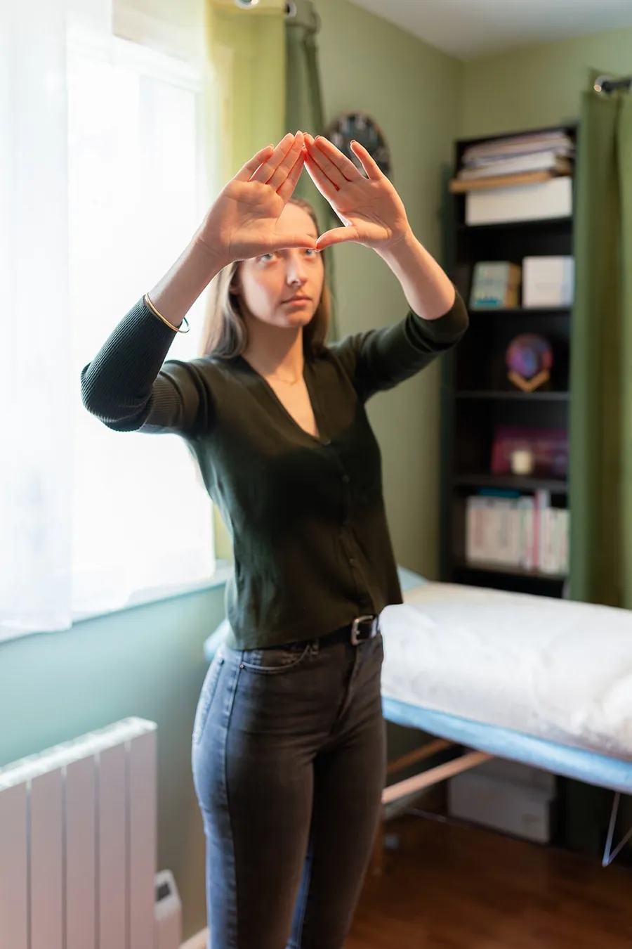Pendant une équilibration, une consultante debout dans le cabinet forme un triangle avec ses mains devant les yeux